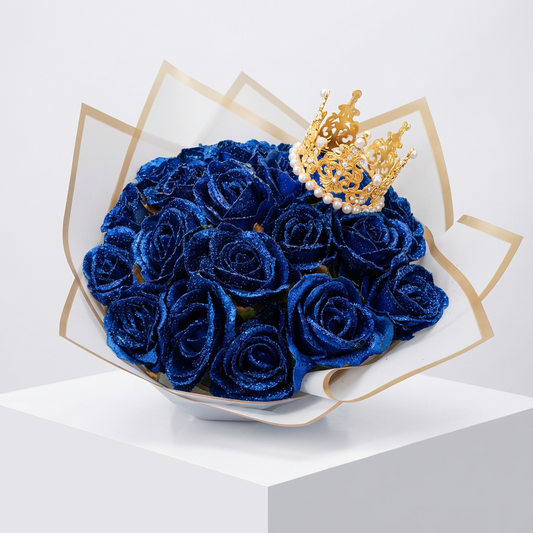 Csillámmal borított, mélykék rózsacsokor, tetején díszes arany koronával, elegáns, arany szegélyű fehér csomagolópapírban, fehér talapzaton.