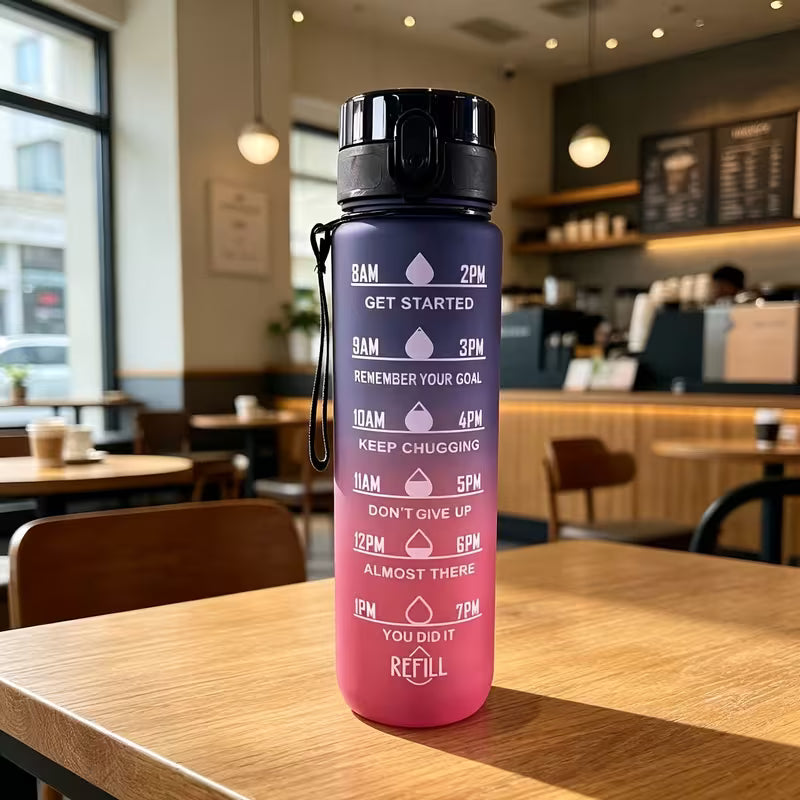 1000 ml-es motivációs kulacs lila-rózsaszín színátmenettel, óránkénti időjelöléssel és motivációs feliratokkal, hordozópánttal